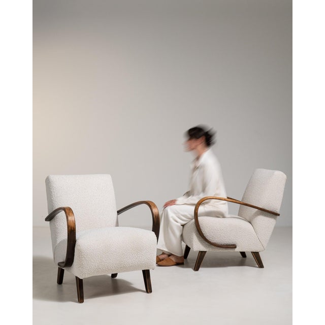 A cream wood armchair by Jindřich Halabala, dating to the 1950s and made in Czechia. The wood frame is finished in fabric,...