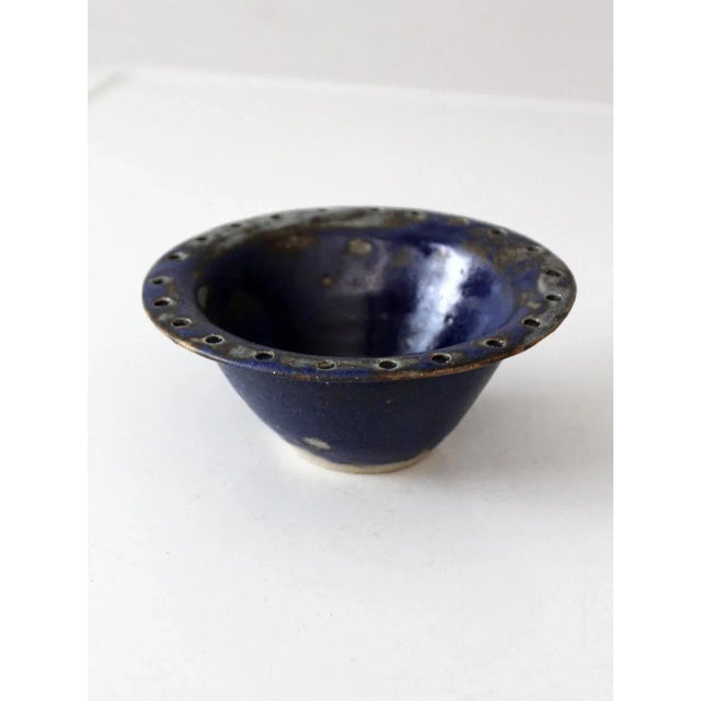 This vintage studio pottery bowl is signed by the artist and showcases a rich, variegated blue glaze. The handmade piece...