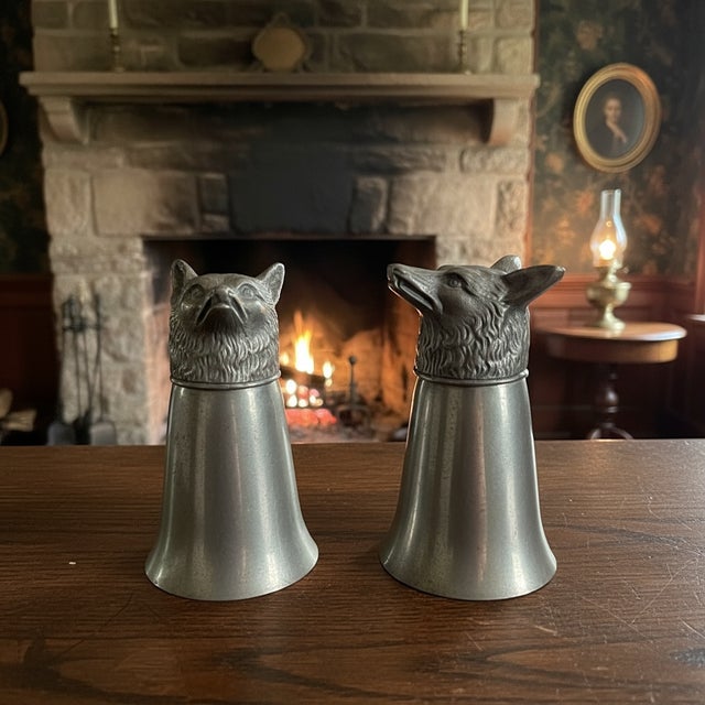 This pair of pewter fox head stirrup cups reflects the long English hunting tradition, where such cups were used for...