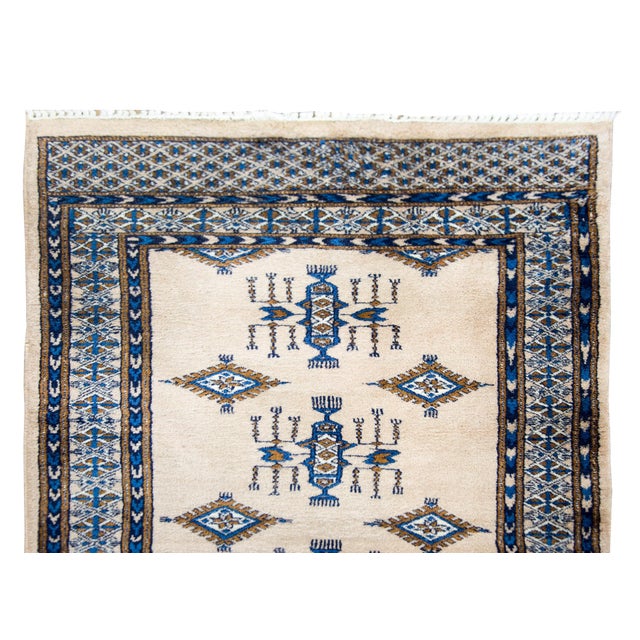 A late 20th century Pakistani Bokhara runner with many large diamond medallions and repeated stylized floral motifs...
