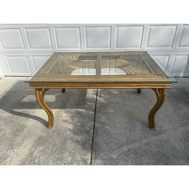 This beautiful wicker and rattan dining set features a solid glass-top table paired with six matching fan-back chairs,...