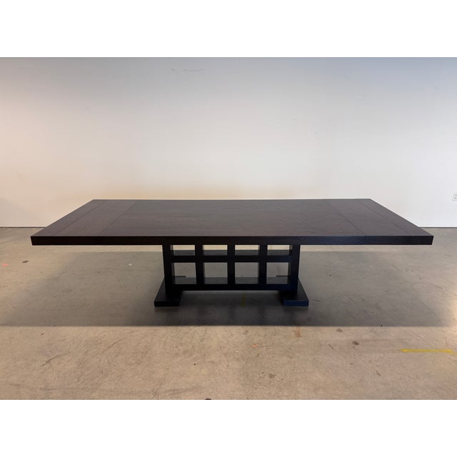 A striking dining table with a strong architectural presence. The thick top is in a deep, dark-stained oak that lets the...