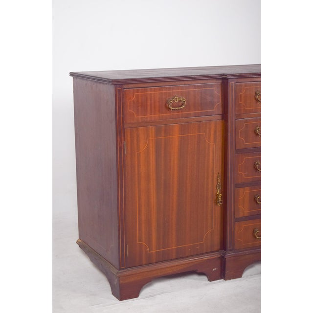 English sideboard with marquetry work. Characterized by a symmetrical and well-proportioned structure with a satin...
