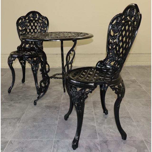An exceptionally decorative cast iron garden set, comprising two matching chairs and a round table in a richly detailed...