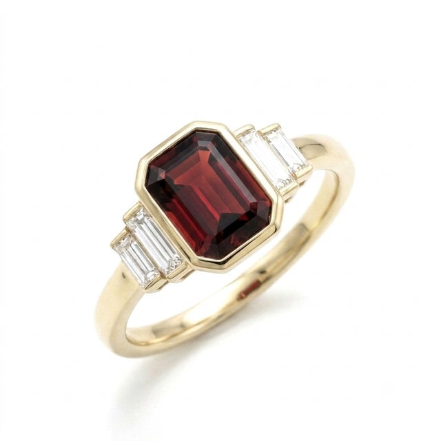 Refined and architectural, this stunning ring features a rich, deep-toned 7x5mm emerald-cut gemstone, secured in a sleek,...