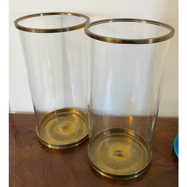 Pair large Ralph Lauren brass and glass hurricane candle shades. Each glass globe with separate brass base and collar at...