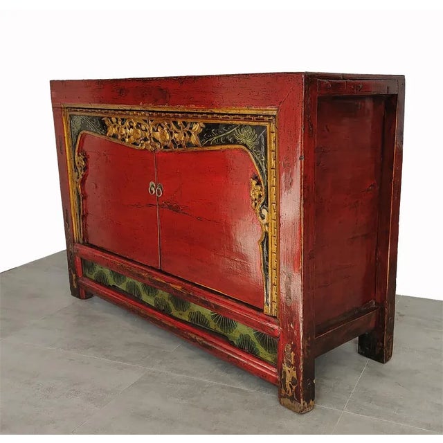 This red cabinet in a warm antique red has two doors with carved gold and black borders which open to a large cabinet with...