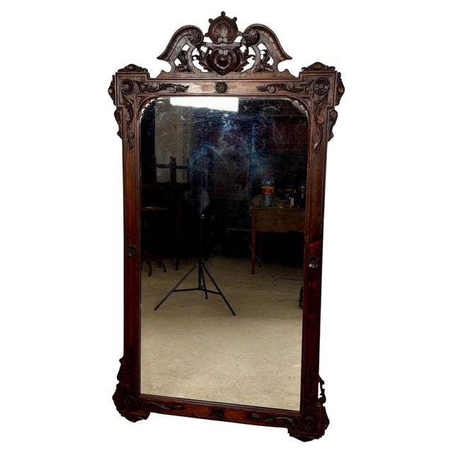 Large antique wall mirror featuring an elaborately hand-carved frame with exceptional decorative detailing. The mirror is...