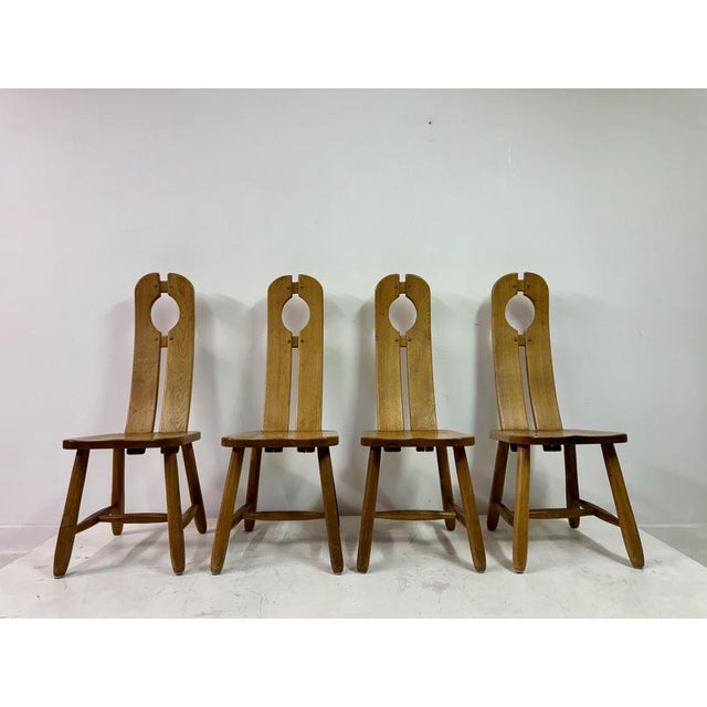 Set of four oak dining chairs by De Puydt This is a set of four solid oak dining chairs featuring a distinctively rustic...