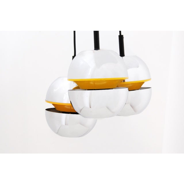 A striking space-age pendant chandelier featuring three sculptural, rounded light forms suspended from slender black...