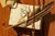 Painting depicts a knotty pine wall with attached objects including a hand written letter with a pendant magnifying glass,...