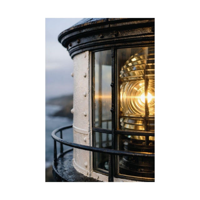 Architectural coastal artwork highlighting the luminous geometry of a lighthouse Fresnel lens, where layered glass prisms...