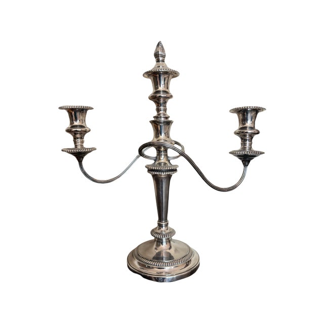 A beautiful pair of silver-plated three-light candelabras—featuring a central flame-form finial, curved arms, and...