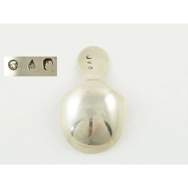 An early 19th C French silver caddy spoon. The caddy spoon is embellished with a bright-cut engraving of drapery valance...