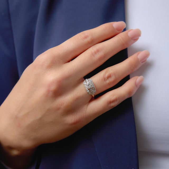 This elegant Art Deco engagement ring centers on a sparkling round brilliant cut diamond weighing approximately 0.55...