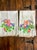 two white hand towels decorated with colorful hand-painted designs, Each towel features an identical artwork theme, with...
