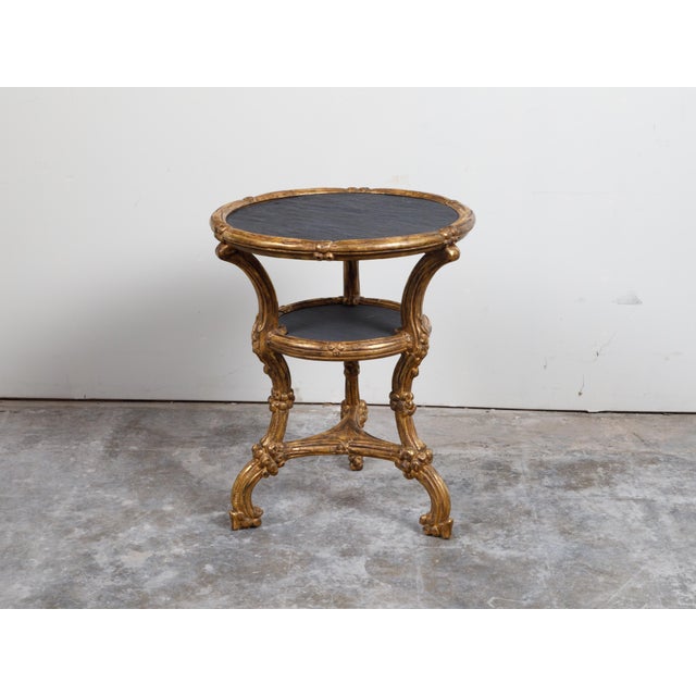 An Italian giltwood side table from the early 20th century, with slate top, shelf and cabriole legs. Created in Italy...