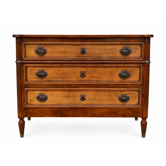 A Louis XVI style light walnut chest of drawers with three drawers adorned with fluted motifs and gilt handles. Very good...