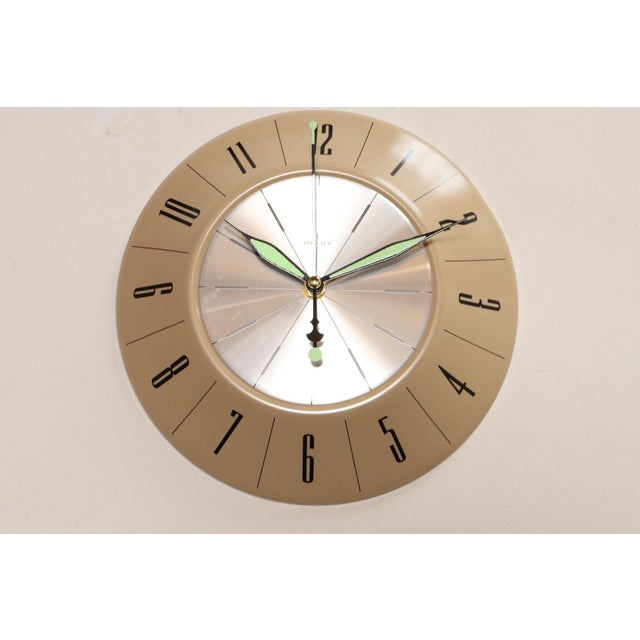 Welby wall clock with beige enameled metal frame, silver clock face, and black numerals (ca. late 1940s/early 1950s,...