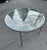 This round, 1970’s modern-style table featuring a clear glass tabletop set on a chrome frame. The tabletop is circular,...