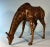 This majestic bronze sculpture intricately portrays the grace and beauty of a giraffe in a natural, feeding pose. The...