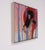 This artwork features a figure partially draped in an umbrella, set against a backdrop of tall, slender trees that evoke a...
