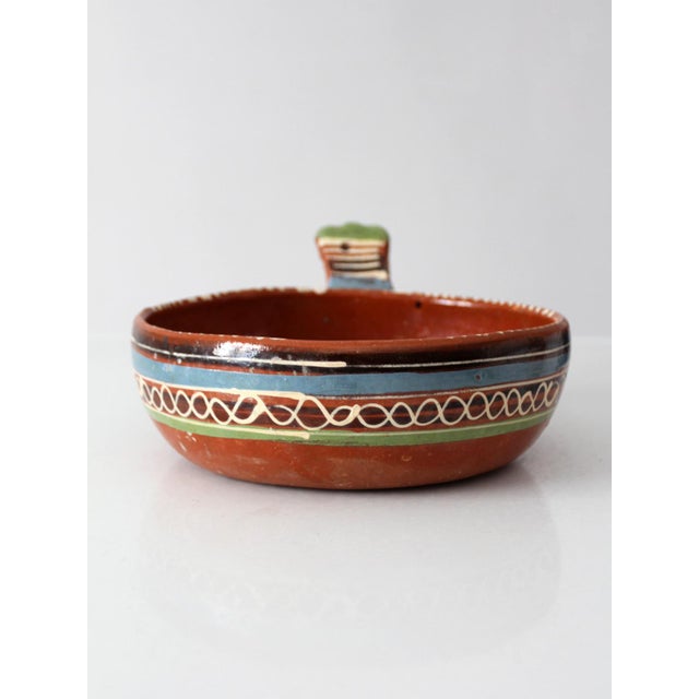 Mid-century Mexican pottery handled dish featuring hand-painted bands in blue, green, black, and cream over warm...
