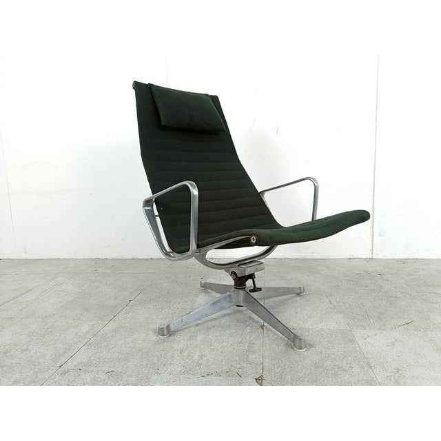 Elegant and timeless Eames EA124 swivel chair. The chair is upholstered in the original black fabric. The chair has a tilt...