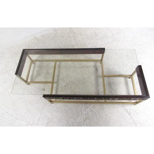 This unique designer coffee table features an offset glass tabletop mounted on a brass and carved wood base. Sturdy Mid-...