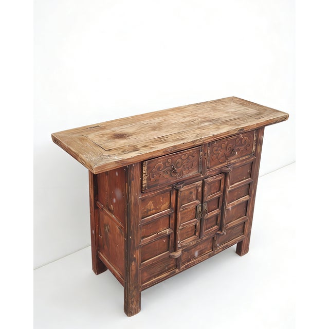 Dating to 1806, this antique sideboard is made from solid elm wood, showcasing a hand-carved facade with deep scrolling...
