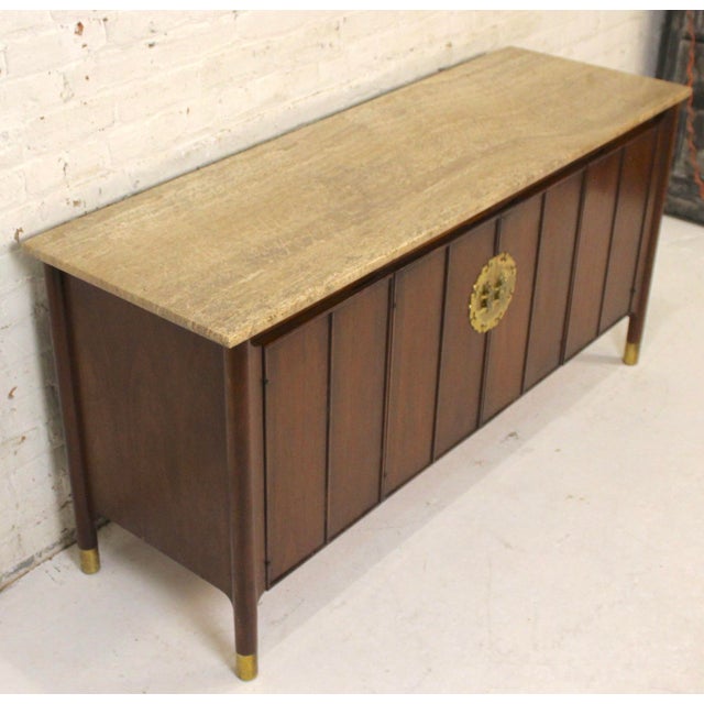 This is a stunning travertine topped walnut credenza. This piece is in the Hollywood Regency style. This piece is accented...