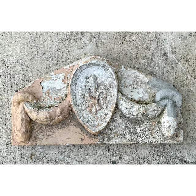 This vintage cement architectural fragment showcases a classical pediment form, its triangular silhouette centered around...