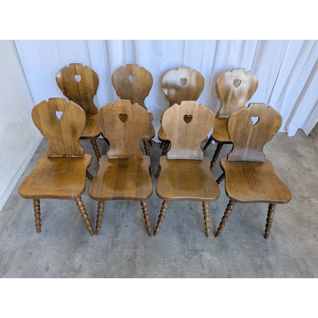 Set of 8 vintage wooden dining chairs in Tyrolean style. The chairs feature solid wooden construction with bobbin-turned...