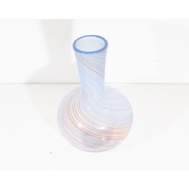 A glass vase produced by Dansk. The vase features a blue and orange spiraled pinstripe design.