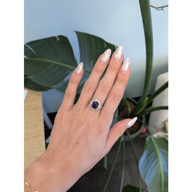 A GIA-certified Ceylon sapphire anchors this cushion-cut ring, its rich blue wrapped in a brilliant halo of diamonds and...