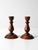 A pair of vintage wood candlestick holders featuring classic turned forms in rich warm wood tones with softly aged...