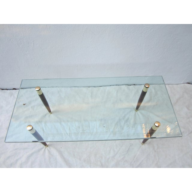 Elegant glass coffee table with brass and mahogany legs that sandwich the glass with brass caps on top. Great looking...