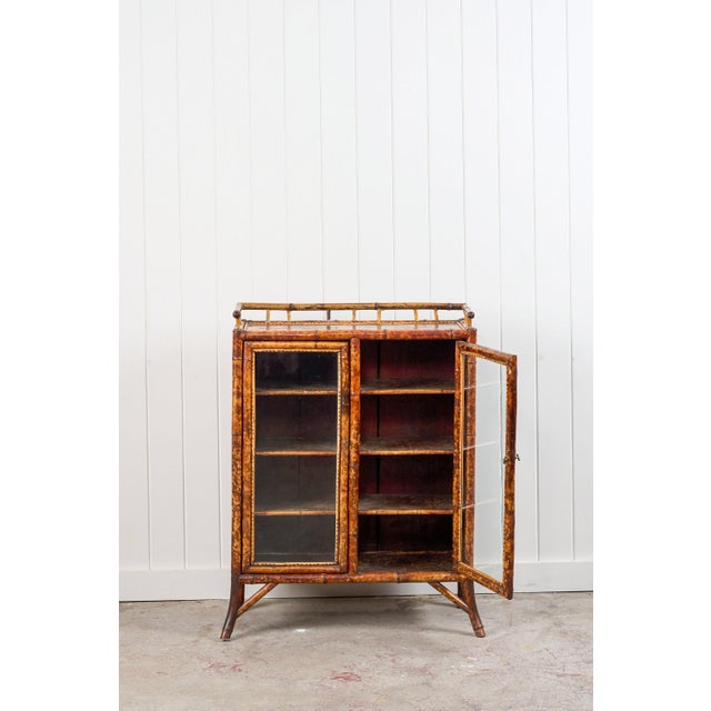 This antique Victorian tiger bamboo glazed bookcase cabinet (c. 1870) features richly mottled tiger bamboo and an upper...
