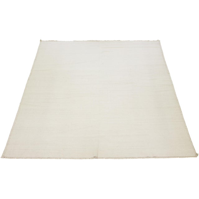 This flatweave rug showcases a modern Dhurrie design with a beige base color and decorative accents along the border. This...