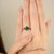 This elegant three-stone ring showcases an oval-cut 2.1Ct natural emerald at the center, flanked by two baguette-cut...