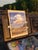 This oil painting on masonite captures a serene coastal landscape, showcasing gentle waves lapping against rocky shores...