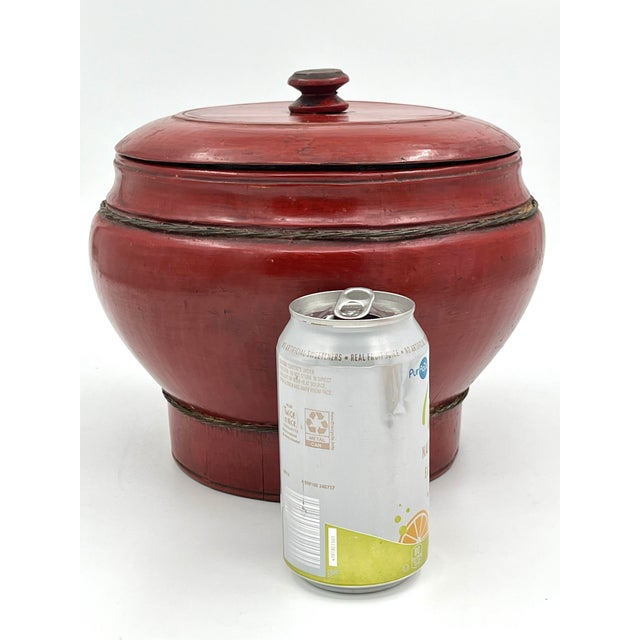 Antique Chinese red-lacquered round wood box or rice bucket with lid. Made of wood with twisted metal trim. Round, squat...