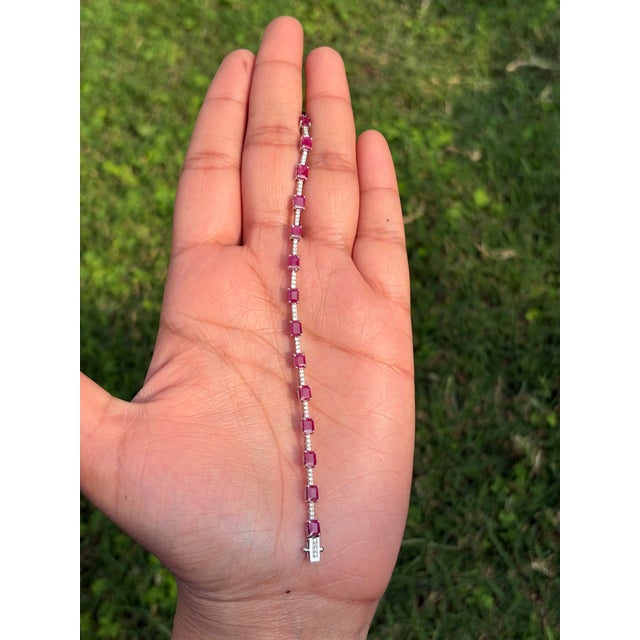 This modern tennis bracelet features a 5.95 carat natural ruby and diamonds, set in 14K white gold. Each measuring...