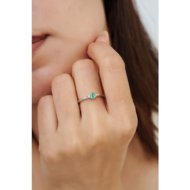Crafted in 925 sterling silver, this delicate ring features a 0.26 carat pear-cut emerald accented by sparkling diamonds...