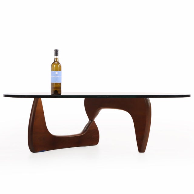 A walnut coffee table by Noguchi for Herman Miller. The design was created in 1944 having a glass plate atop two...