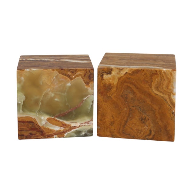 A pair of cube shaped bookends made of onyx. The highly decorative stone is richly banded and has swirling patterns in...