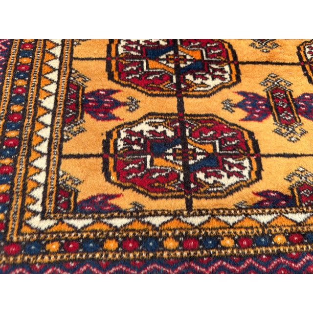 This is a vintage Turkmen Beshir rug, hand-knotted with wool. It features a golden-yellow field with repeating Beshir gul...
