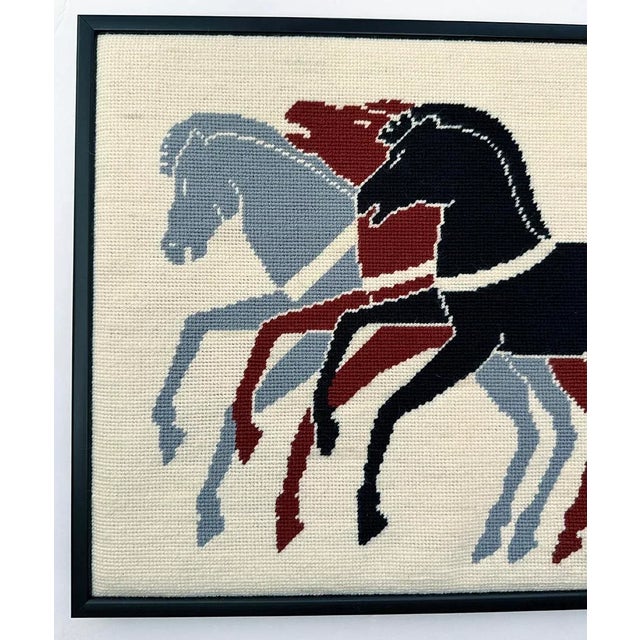 Framed needlepoint of 3 horses. Needle work has been hand stitched with wool yarns. Warm white background with three...