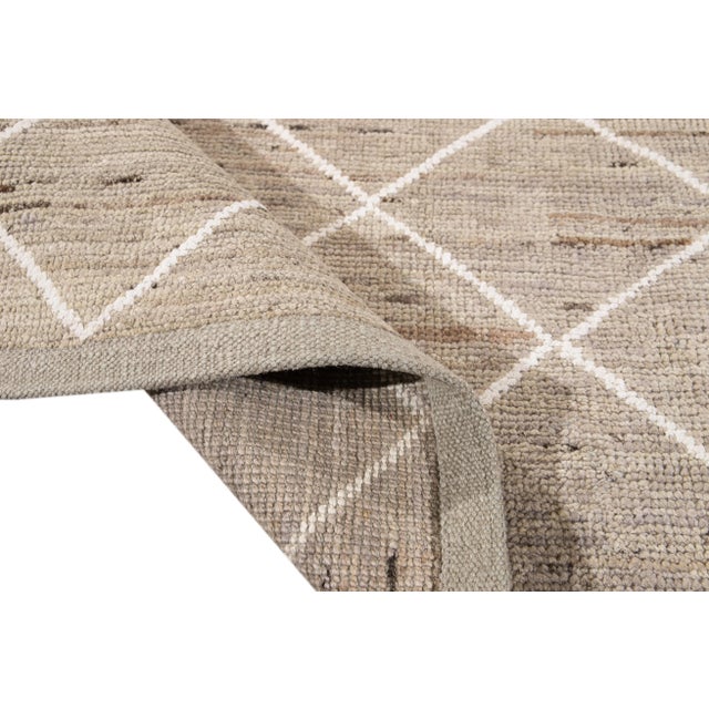 Beautiful Moroccan-style hand-knotted wool rug with a beige field. This Rug has accents of white in a gorgeous all-over...