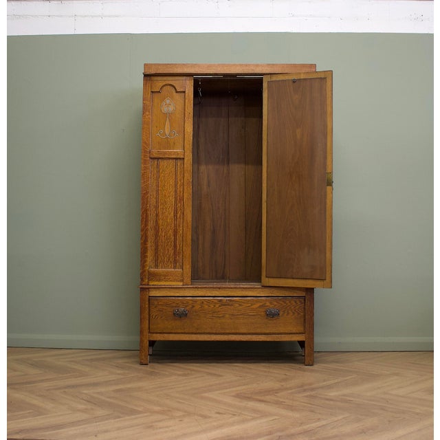 An Edwardian oak wardrobe dating from circa 1900s, with Arts & Crafts styling and elegant Art Nouveau metal inlay....